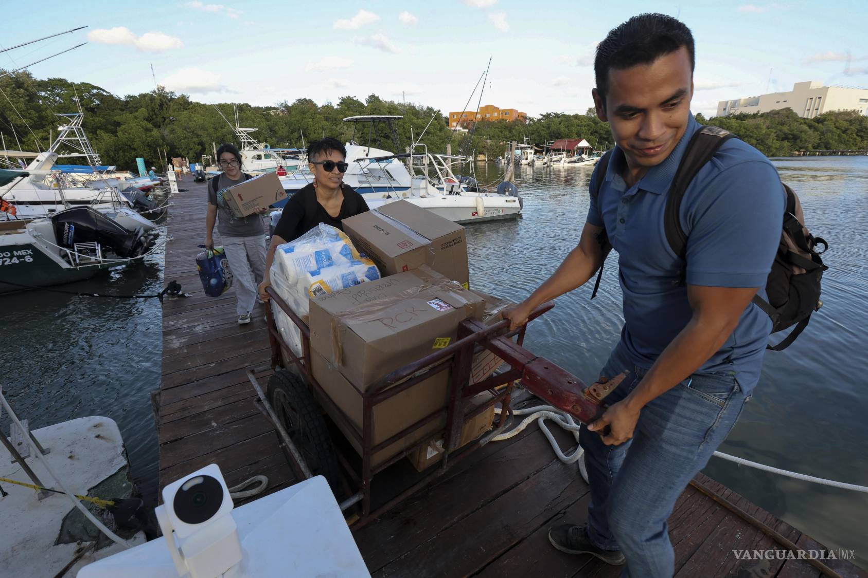 $!Personas cargan paquetes con ayuda humanitaria para un barco que zarpó hacia Cuba.